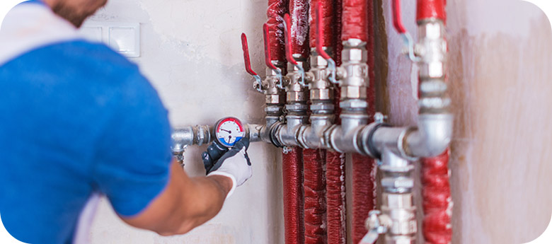 A technician provides excellent plumbing service by maintaining a pipe manifold.